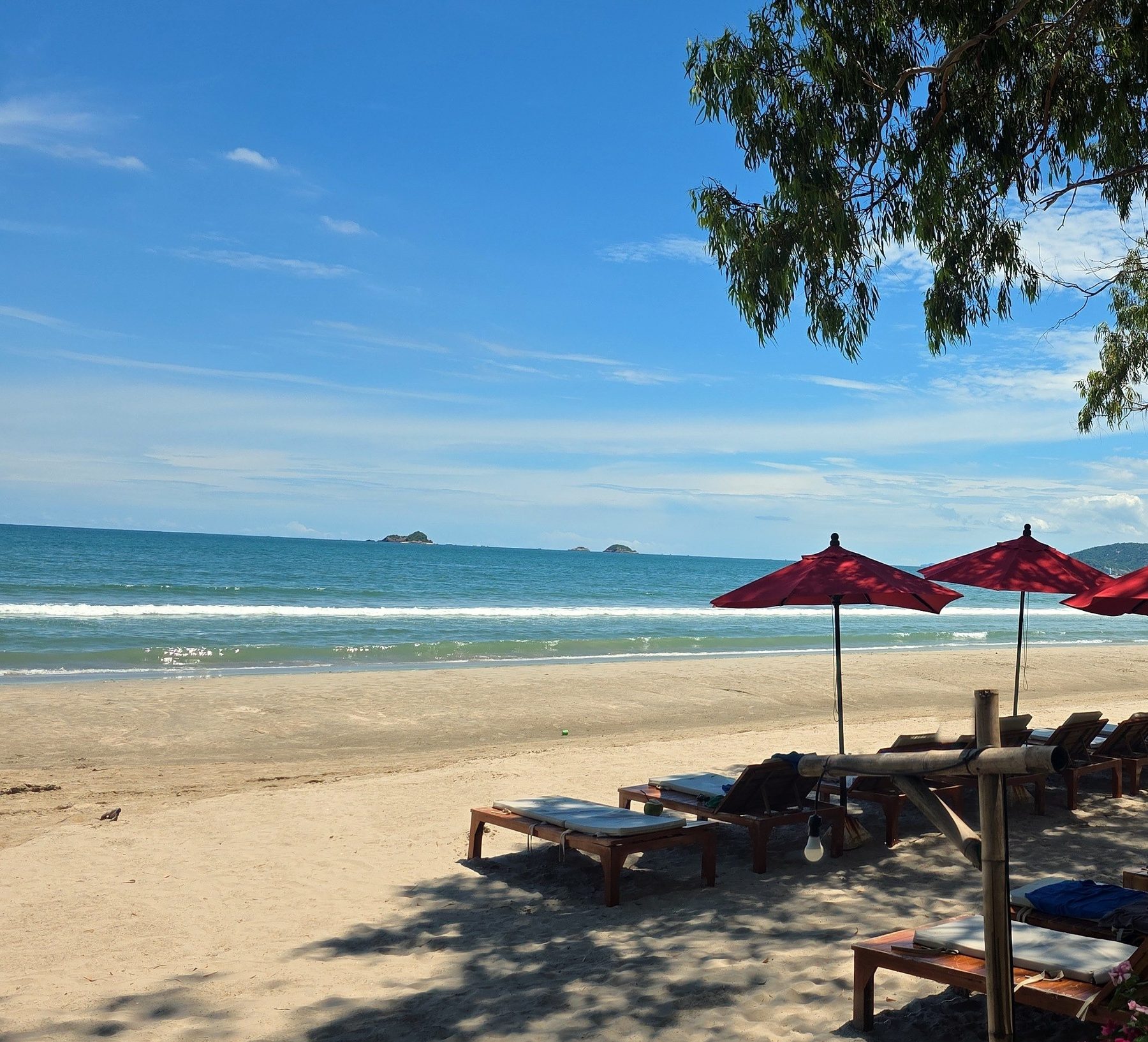 Red umbrellas and sun loungers facing the sea at Khao Takiab